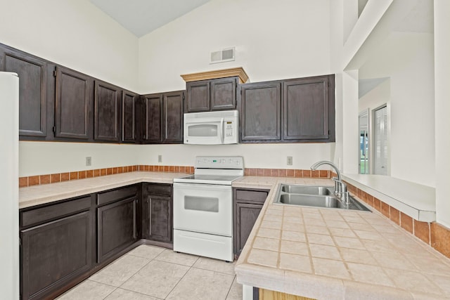 kitchen with white appliances, high vaulted ceiling, sink, dark brown cabinetry, and kitchen peninsula