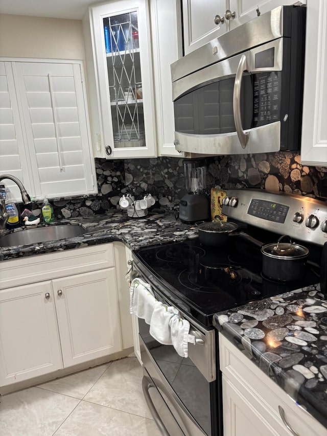 kitchen featuring sink, stainless steel appliances, tasteful backsplash, white cabinets, and light tile patterned flooring