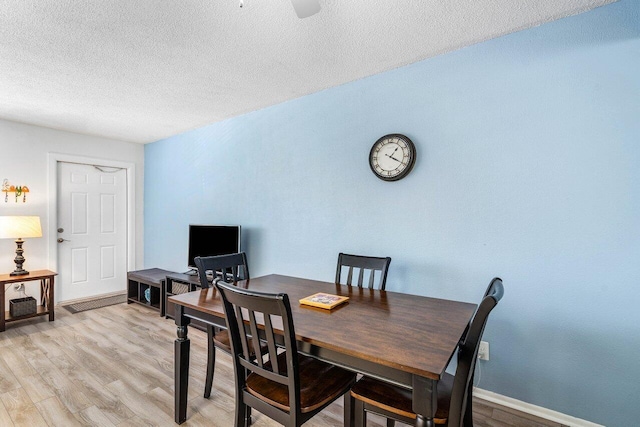 dining room with light hardwood / wood-style floors and a textured ceiling