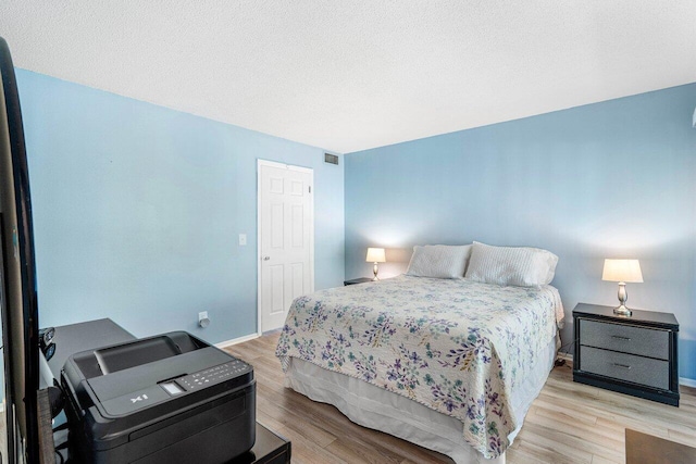 bedroom featuring a textured ceiling and light hardwood / wood-style flooring