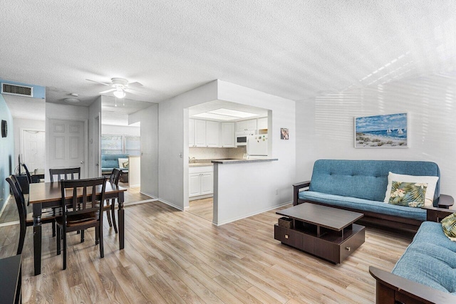 living room featuring a textured ceiling, light hardwood / wood-style floors, and ceiling fan