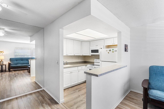 kitchen with kitchen peninsula, a textured ceiling, white appliances, white cabinets, and light hardwood / wood-style floors