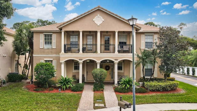 view of front of house featuring a front yard, a balcony, and covered porch