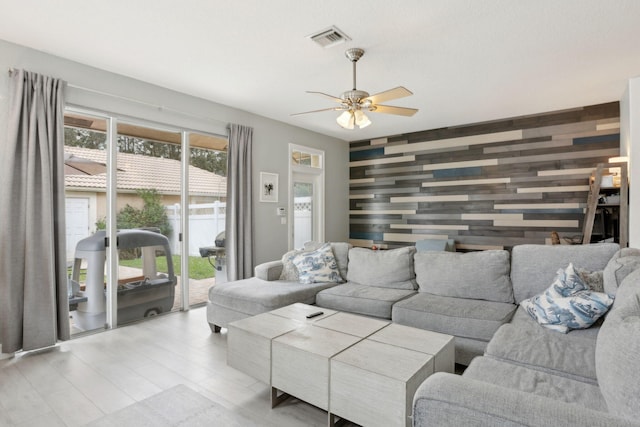 living room featuring ceiling fan and wooden walls