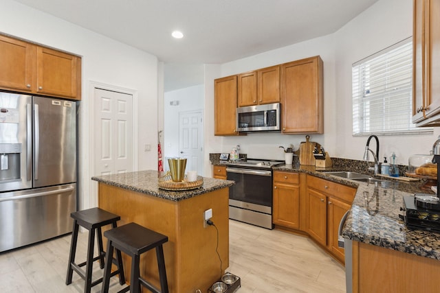 kitchen with a center island, stainless steel appliances, a breakfast bar, dark stone countertops, and sink