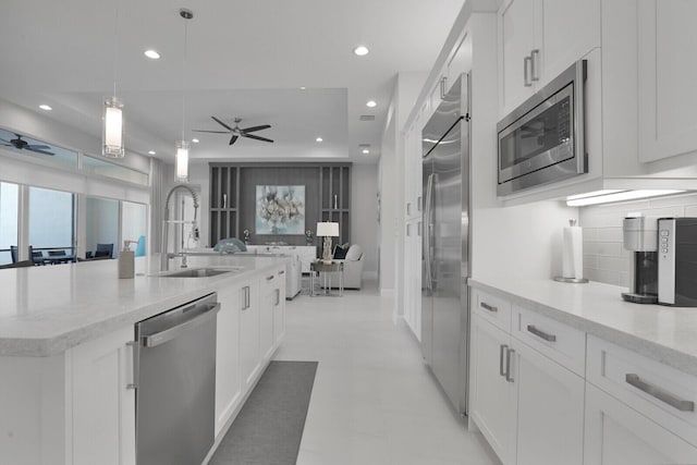 kitchen featuring sink, built in appliances, white cabinetry, and a center island with sink