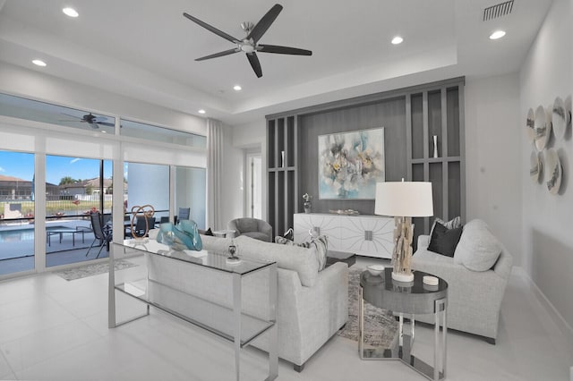 living room featuring ceiling fan and a raised ceiling