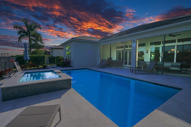 pool at dusk featuring an in ground hot tub and a patio area