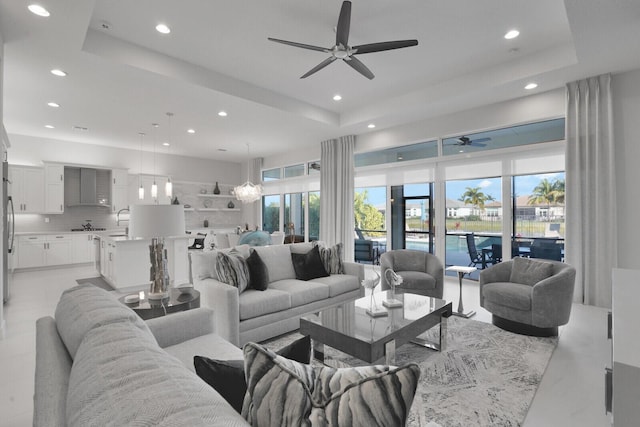 living room with ceiling fan and a tray ceiling