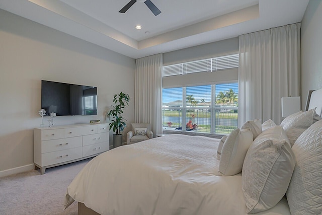 carpeted bedroom featuring a raised ceiling and ceiling fan