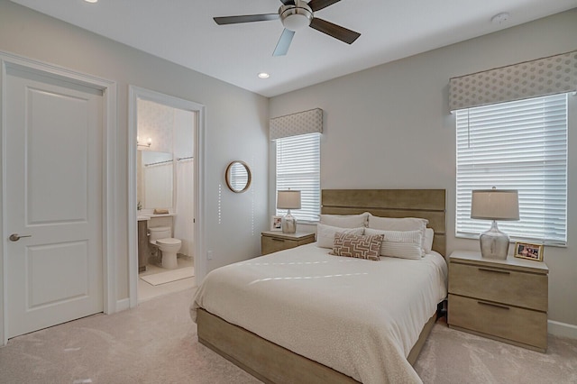 bedroom featuring ceiling fan, light carpet, and ensuite bath