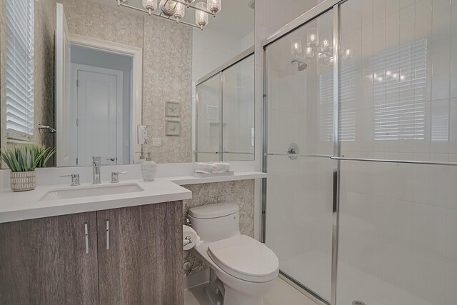 bathroom featuring toilet, an inviting chandelier, an enclosed shower, and vanity