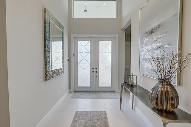 foyer with french doors, a towering ceiling, and light tile patterned floors