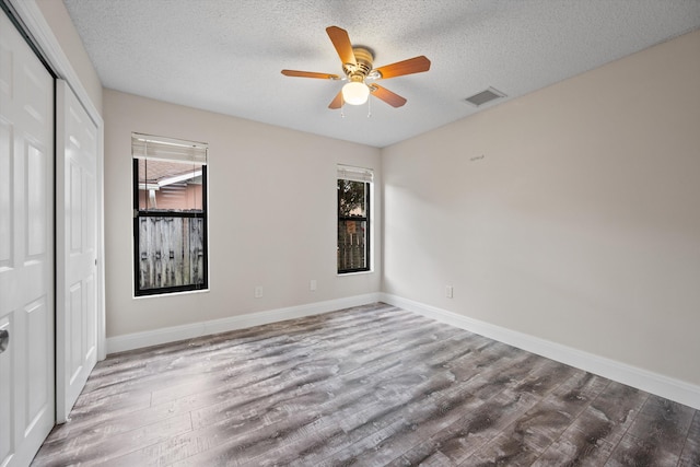 unfurnished bedroom featuring a textured ceiling, a closet, hardwood / wood-style flooring, and ceiling fan