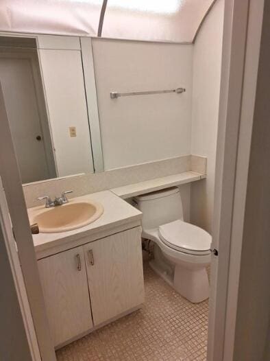 bathroom featuring tile patterned flooring, vanity, and toilet