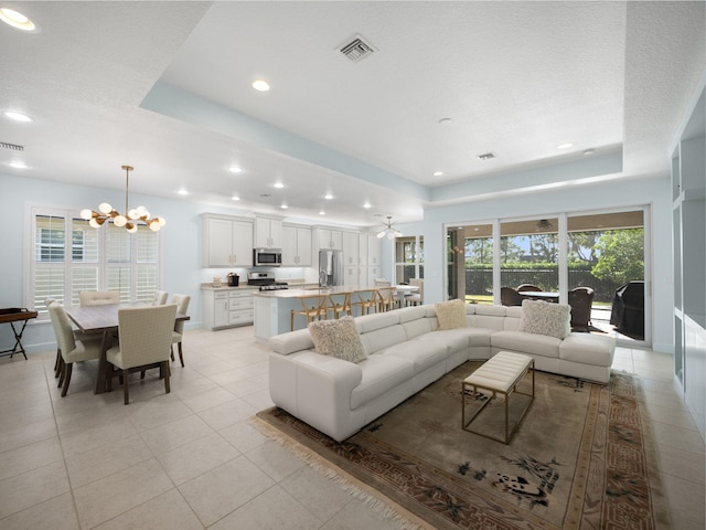 tiled living room featuring a chandelier and a raised ceiling