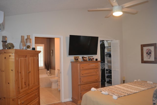 tiled bedroom with ceiling fan, connected bathroom, a closet, and a wall mounted air conditioner