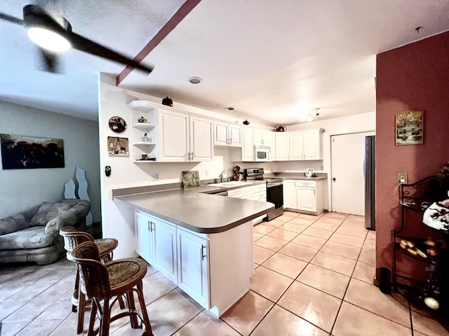 kitchen featuring kitchen peninsula, appliances with stainless steel finishes, sink, white cabinets, and light tile patterned flooring