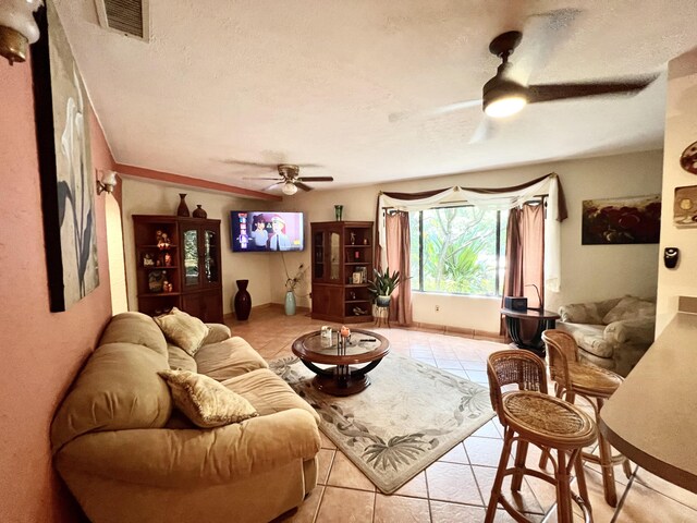 living room featuring a textured ceiling, ceiling fan, and light tile patterned flooring