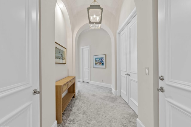 hallway featuring light carpet and an inviting chandelier