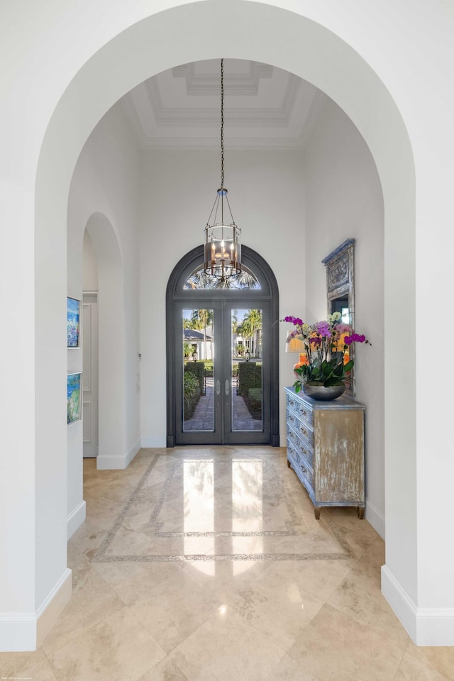 entrance foyer featuring french doors, a raised ceiling, crown molding, a notable chandelier, and a high ceiling