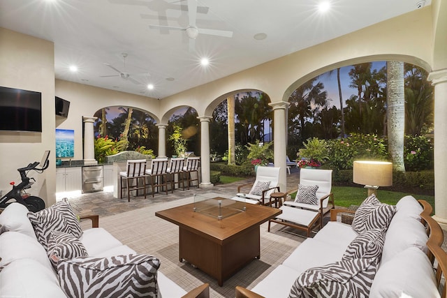 view of patio with ceiling fan, beverage cooler, an outdoor hangout area, exterior bar, and area for grilling