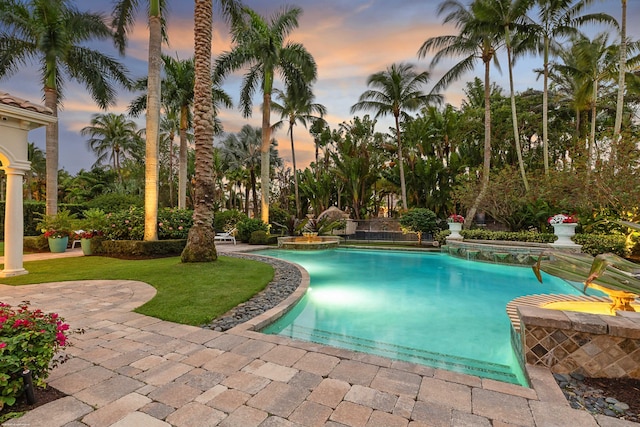 pool at dusk featuring a yard