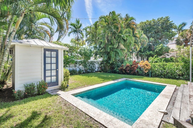 view of pool featuring a storage unit and a lawn