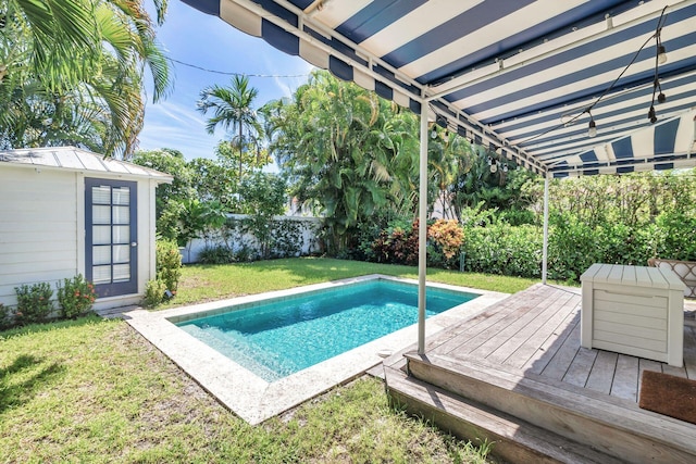 view of swimming pool featuring a lawn, a storage unit, and a wooden deck