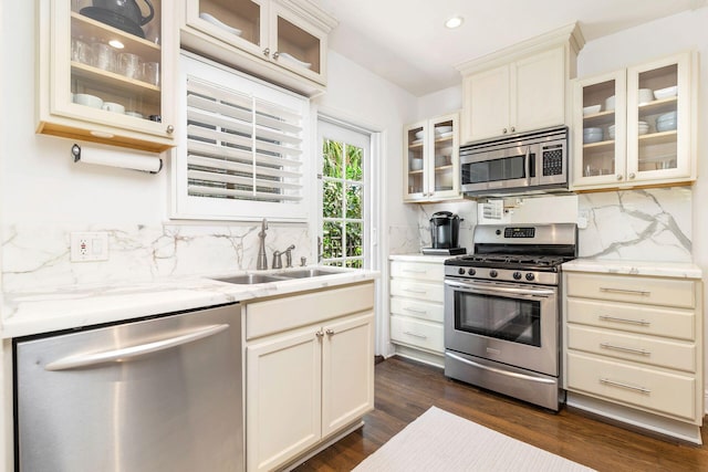 kitchen featuring light stone countertops, dark hardwood / wood-style floors, tasteful backsplash, appliances with stainless steel finishes, and sink