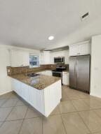 kitchen featuring tile patterned floors, kitchen peninsula, white cabinetry, and stainless steel appliances