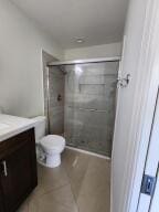 bathroom with a tile shower, tile patterned flooring, vanity, and toilet