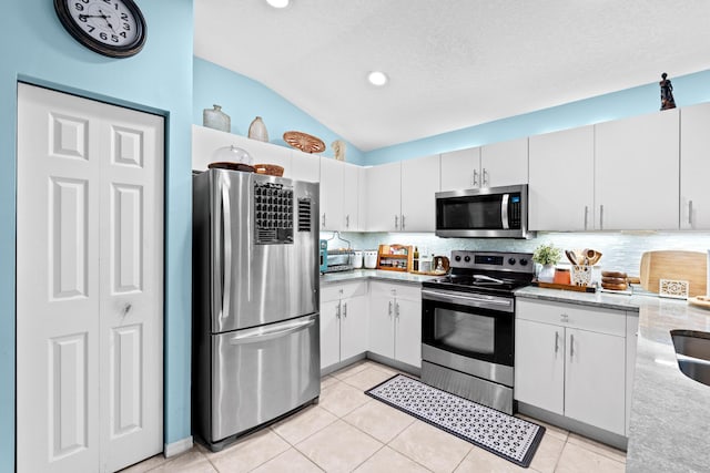 kitchen featuring white cabinetry, stainless steel appliances, and vaulted ceiling