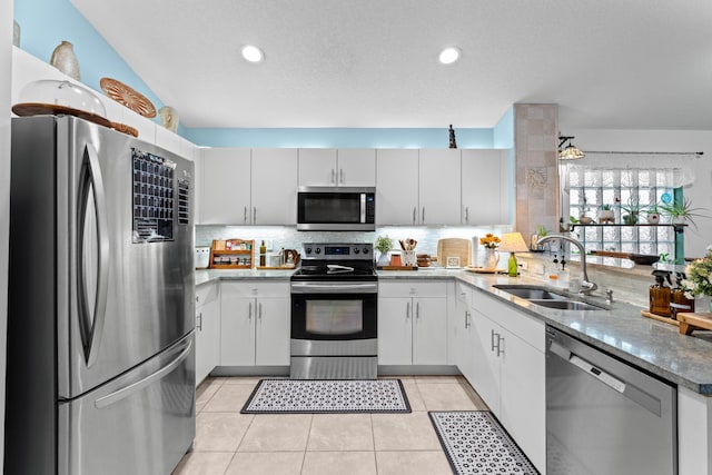 kitchen with backsplash, sink, white cabinetry, stainless steel appliances, and light tile patterned floors