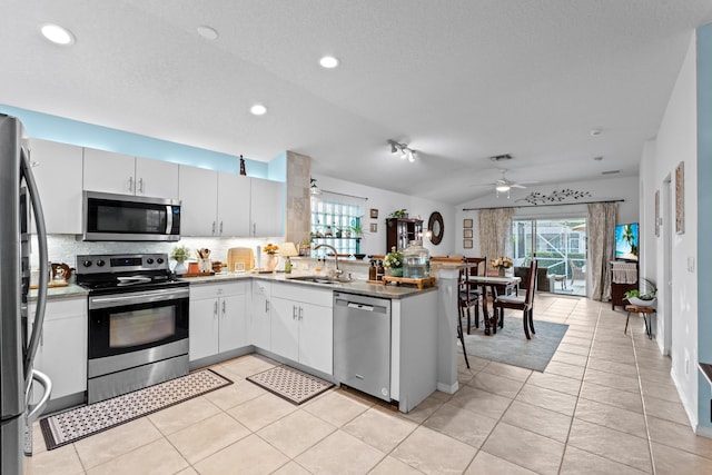 kitchen with white cabinetry, kitchen peninsula, stainless steel appliances, backsplash, and sink