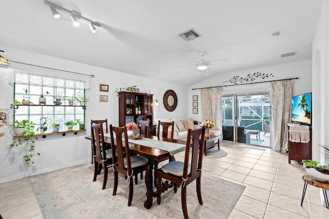 tiled dining space with vaulted ceiling, ceiling fan, and a textured ceiling