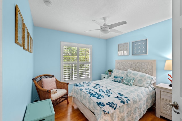 bedroom with ceiling fan, wood-type flooring, and a textured ceiling