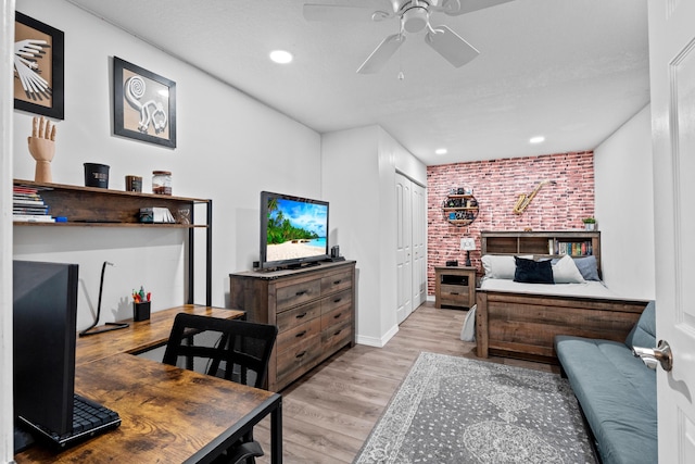 interior space featuring ceiling fan, brick wall, and light wood-type flooring