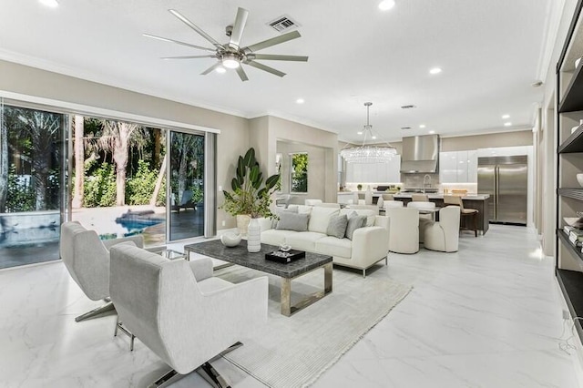 living room featuring crown molding and ceiling fan with notable chandelier