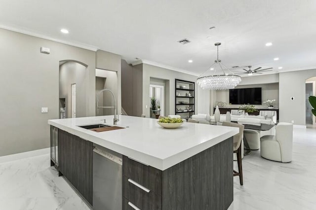 kitchen with hanging light fixtures, dark brown cabinets, sink, and a spacious island