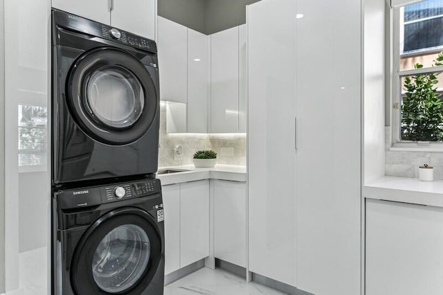 laundry area featuring cabinets and stacked washer and clothes dryer