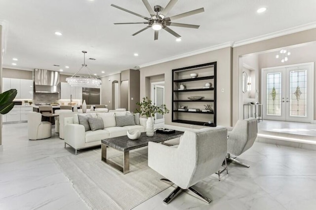 living room with crown molding, ceiling fan with notable chandelier, built in features, and french doors