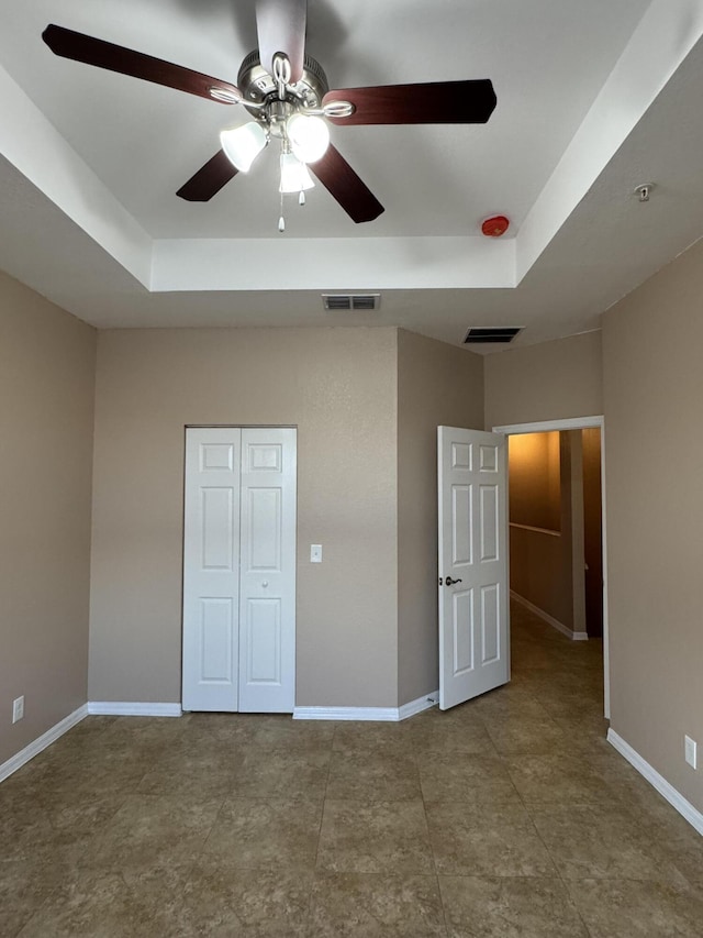 unfurnished bedroom featuring a raised ceiling and ceiling fan