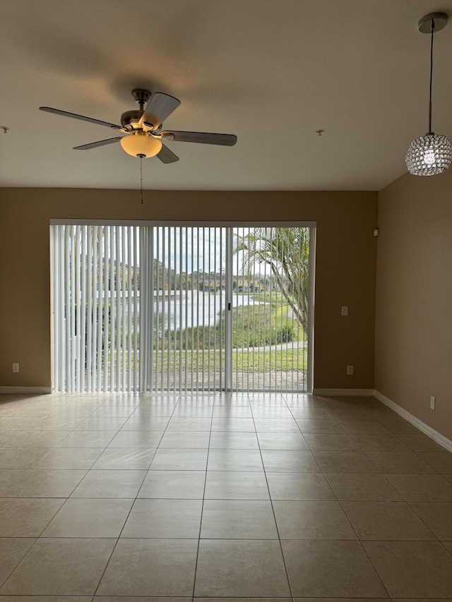 tiled empty room featuring ceiling fan and a water view