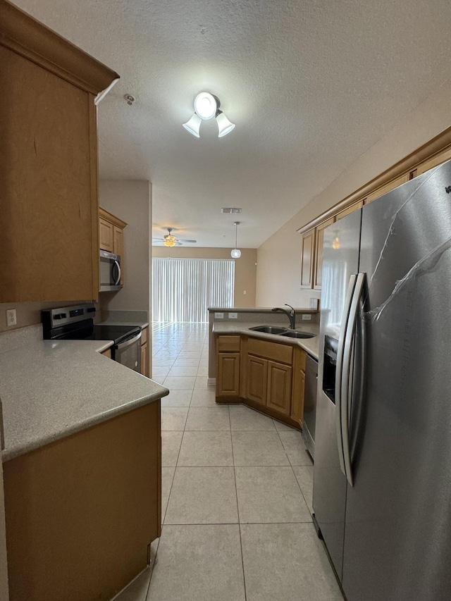 kitchen with ceiling fan, sink, hanging light fixtures, stainless steel appliances, and kitchen peninsula