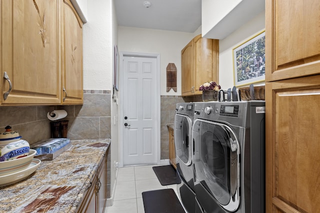 washroom featuring cabinets, washer and clothes dryer, and light tile patterned flooring