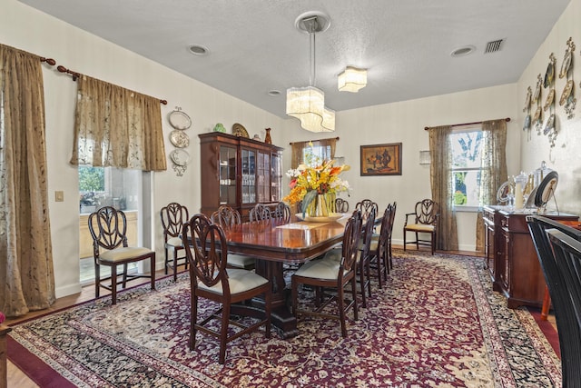 dining area with a textured ceiling, an inviting chandelier, and a wealth of natural light