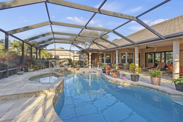 view of pool featuring ceiling fan, a patio, glass enclosure, and an in ground hot tub