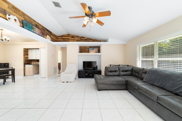 living room with ceiling fan with notable chandelier, vaulted ceiling, and light tile patterned flooring