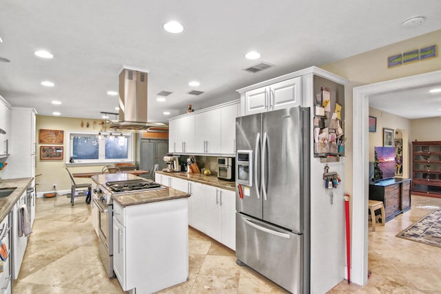 kitchen featuring appliances with stainless steel finishes, dark stone counters, island range hood, white cabinets, and a kitchen island